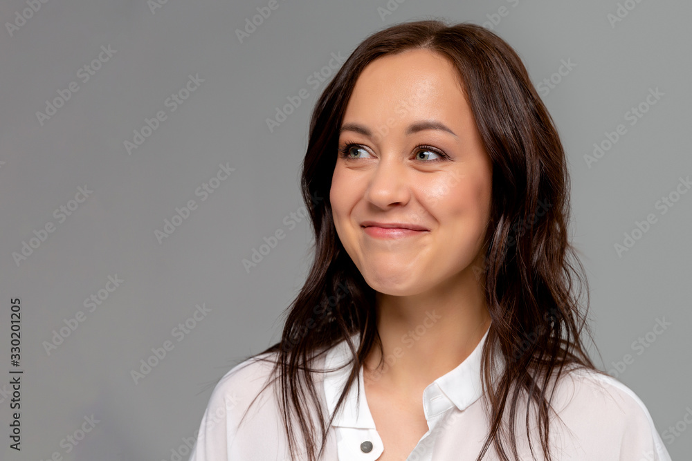Smiling young business woman in white shirt posing isolated on grey wall background studio portrait. Achievement career wealth business concept. Mock up copy space.