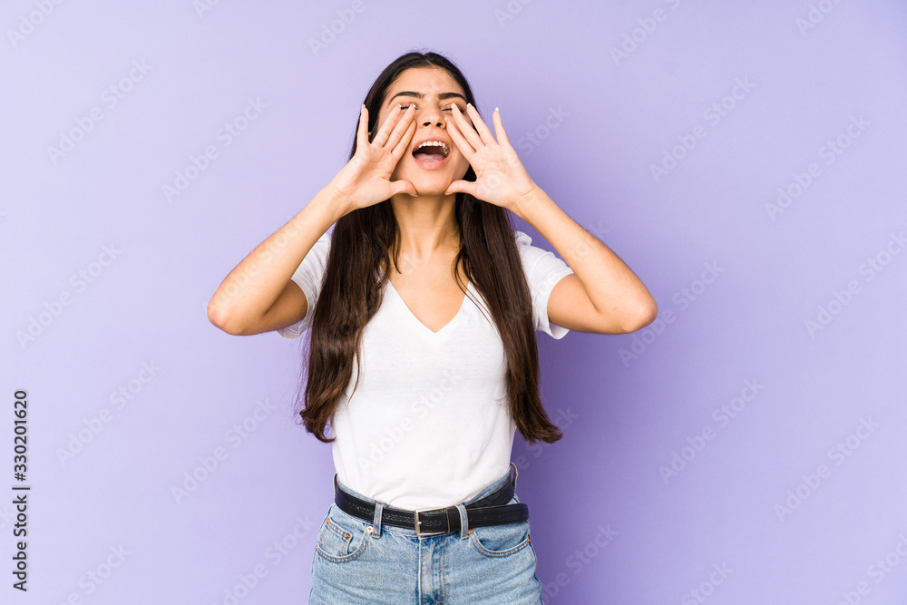 Young indian woman isolated on purple background shouting excited to front. Young indian woman isolated on purple background shouting excited to front.