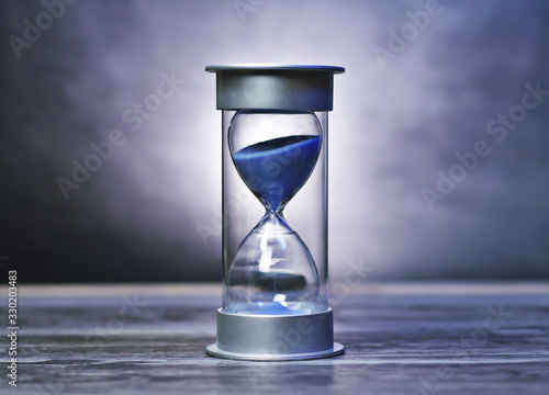 Vintage hour glass with blue sand. A symbol of time