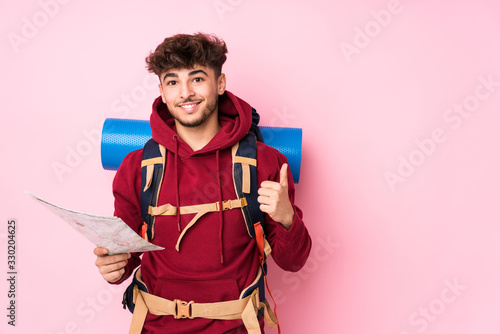 Young arab traveler man holding a map smiling and raising thumb up