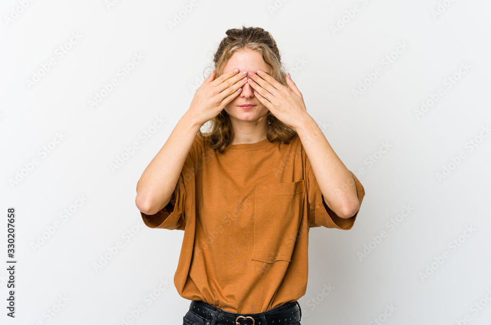 Young caucasian woman on white backrgound afraid covering eyes with hands.