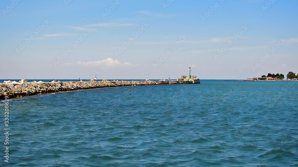 View to the big breakwater surrounded by sea and with signal light at the end in Umag, Croatia. View to the big breakwater surrounded by sea and with signal light at the end in Umag, Croatia.