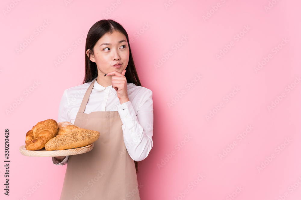 Young chinese baker woman isolated looking sideways with doubtful and skeptical expression. Young chinese baker woman isolated looking sideways with doubtful and skeptical expression.