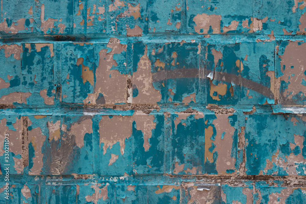 An old tile wall is punctured in tit color. Cracked paint, aged texture, background