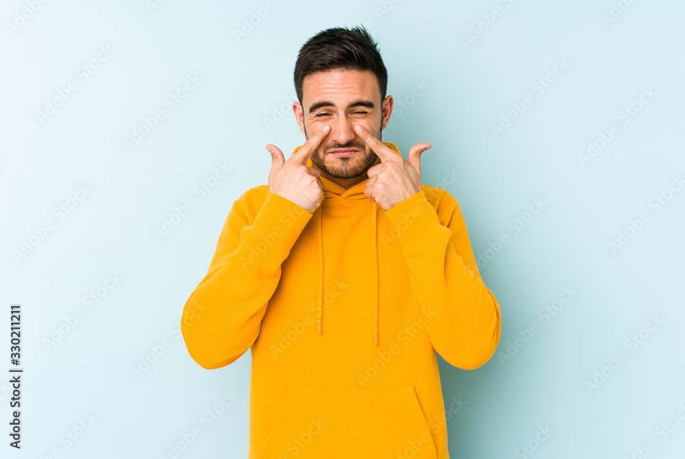 Young caucasian man isolated on blue background crying, unhappy with something, agony and confusion concept. Young caucasian man isolated on blue background crying, unhappy with something, agony and confusion concept.
