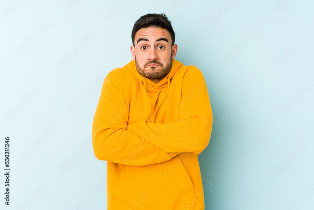 Young caucasian man isolated on blue background shrugs shoulders and open eyes confused. Young caucasian man isolated on blue background shrugs shoulders and open eyes confused.