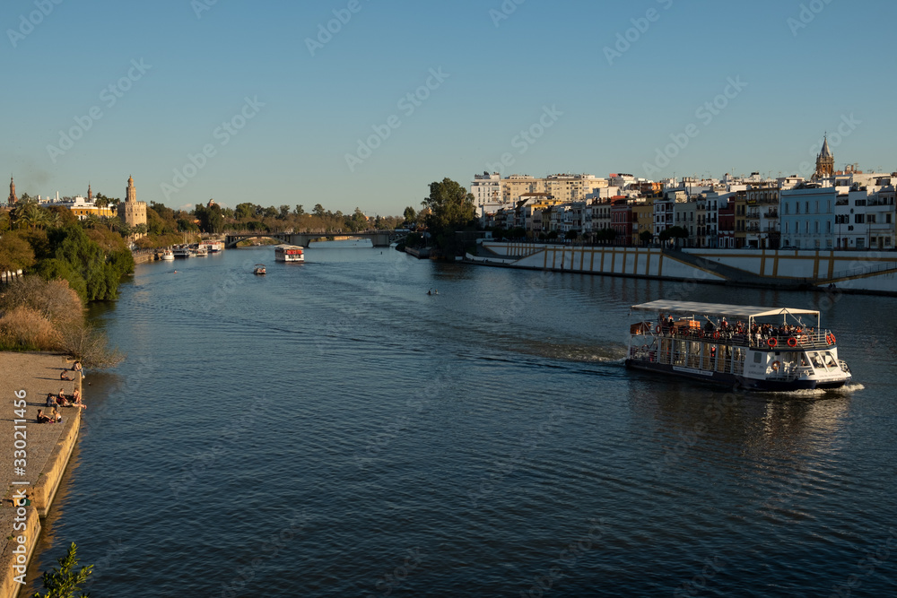 Crucero fluvial por el río Guadalquivir en Sevilla, al fondo la torre del oro y el barrio de Triana