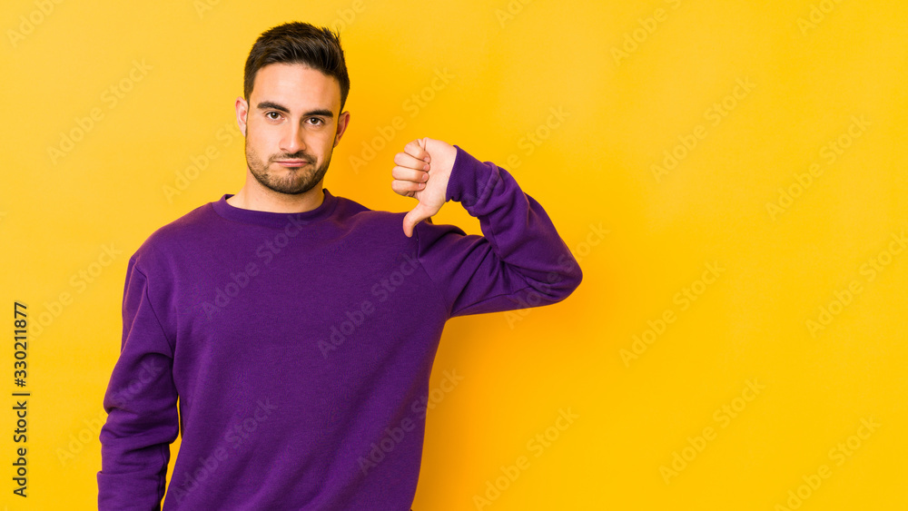 Young caucasian man isolated on yellow bakground showing thumb down, disappointment concept. Young caucasian man isolated on yellow bakground showing thumb down, disappointment concept.