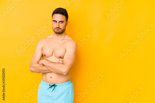 Young caucasian man with swimsuit isolated on yellow background Young caucasian man with trunhappy looking in camera with sarcastic expression.