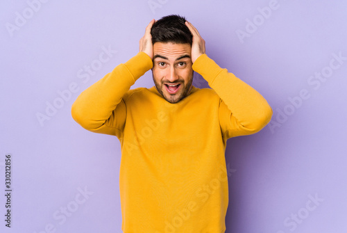 Young caucasian man isolated on purple background screaming, very excited, passionate, satisfied with something.