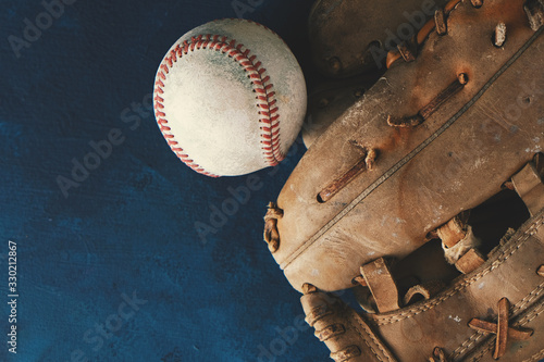 Old baseball glove with ball for sport from top view on blue background.