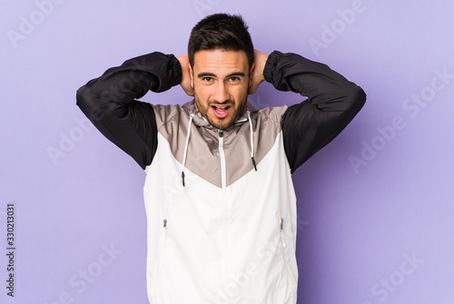 Young caucasian man isolated on purple background screaming with rage. © Asier