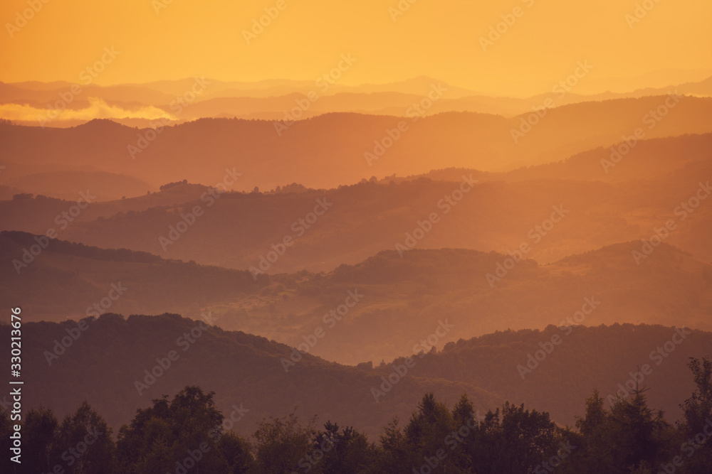 Mountain silhouettes stacked at sunset, from near to distant