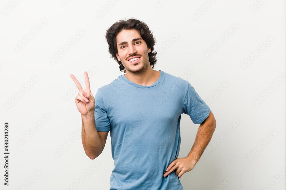Young handsome man against a white background joyful and carefree showing a peace symbol with fingers. Young handsome man against a white background joyful and carefree showing a peace symbol with fingers.