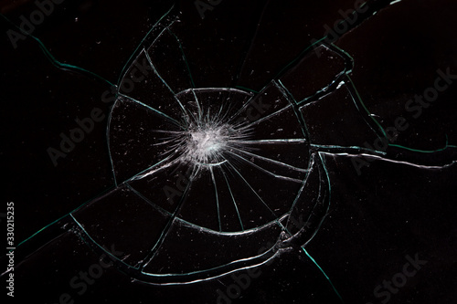 Broken glass with spider web cracks on black background