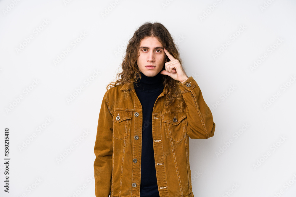 Long hair man posing isolated pointing temple with finger, thinking, focused on a task. Long hair man posing isolated pointing temple with finger, thinking, focused on a task.