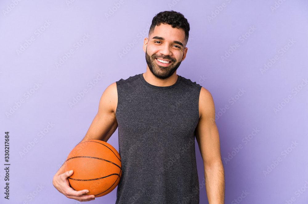 Young latin man playing basket isolated happy, smiling and cheerful.