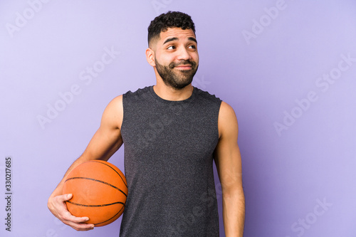 Young latin man playing basket isolated dreaming of achieving goals and purposes