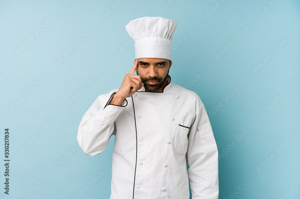 Young latin chef man isolated pointing temple with finger, thinking, focused on a task. Young latin chef man isolated pointing temple with finger, thinking, focused on a task.