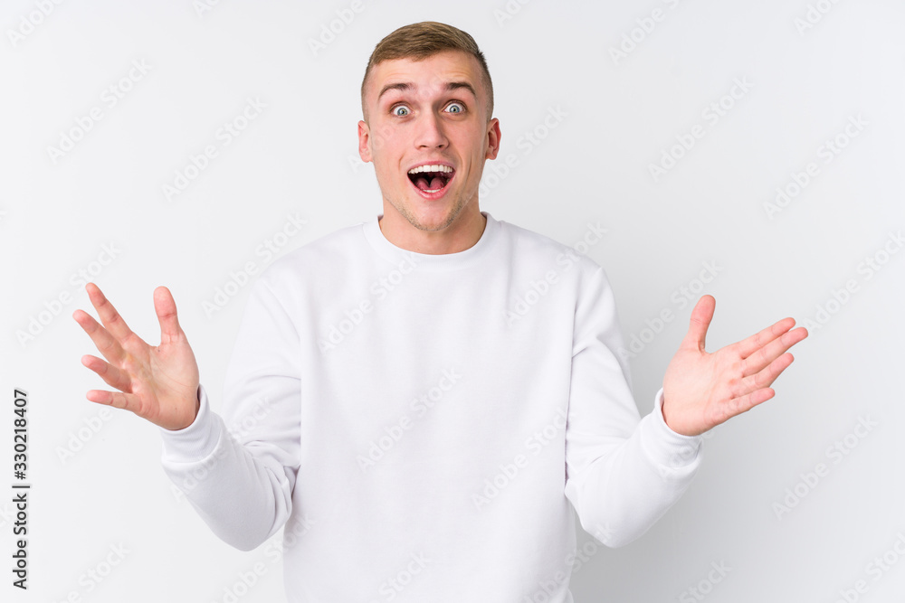 Young caucasian man on white background receiving a pleasant surprise, excited and raising hands. Young caucasian man on white background receiving a pleasant surprise, excited and raising hands.