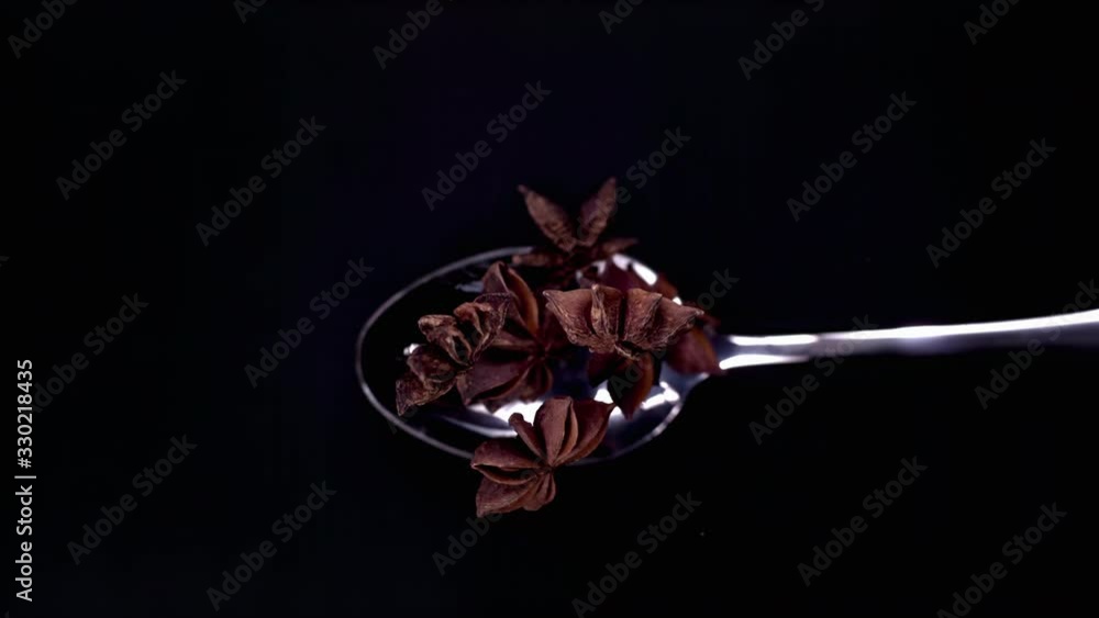 A Full Spoon Of exotic Christmas spice cinnamon anise and nutmeg falling down on black background closeup in super slow motion A Full Spoon Of exotic Christmas spice cinnamon anise and nutmeg falling down on black background closeup in super slow motion