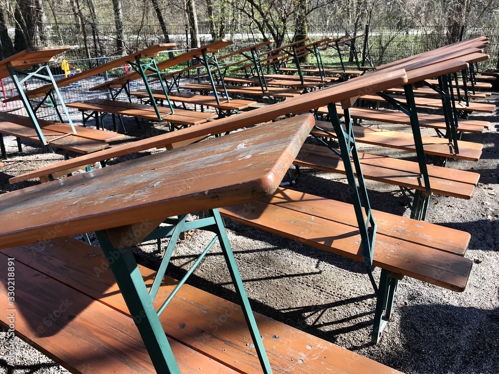 Biergarten mit Tischen und Bänken in einem Park im englischen Garten Biergarten mit Tischen und Bänken in einem Park im englischen Garten
