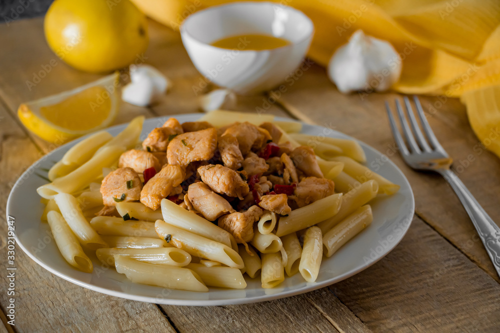 Penne pasta with chicken in a creamy sauce on a light wooden background. Penne pasta with chicken in a creamy sauce on a light wooden background.