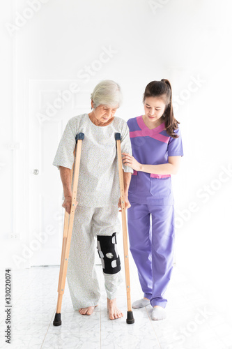 asian old learning to use crutches with female healthcare worker, walk training and rehabilitation, elderly health promotion