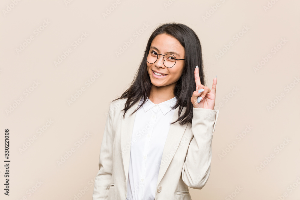 Young business chinese woman showing a horns gesture as a revolution concept. Young business chinese woman showing a horns gesture as a revolution concept.