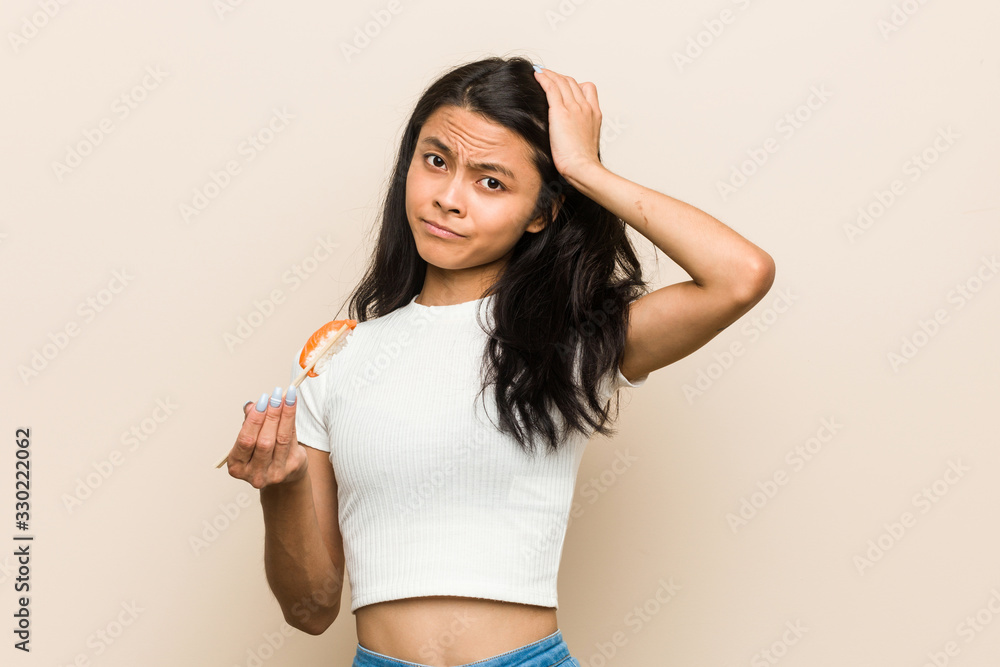 Young asian woman holding a sushi piece being shocked, she has remembered important meeting. Young asian woman holding a sushi piece being shocked, she has remembered important meeting.