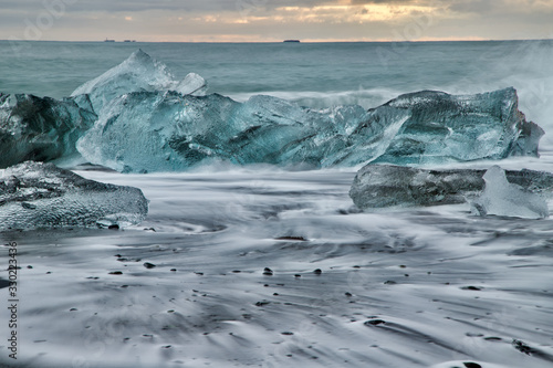 Fototapeta Naklejka Na Ścianę i Meble -  Iceberg on the black beach and white wave captured with long exposure