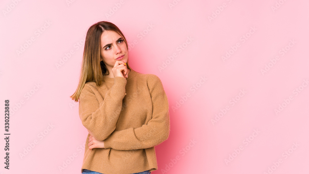 Young caucasian woman isolated on pink background looking sideways with doubtful and skeptical expression. Young caucasian woman isolated on pink background looking sideways with doubtful and skeptical expression.