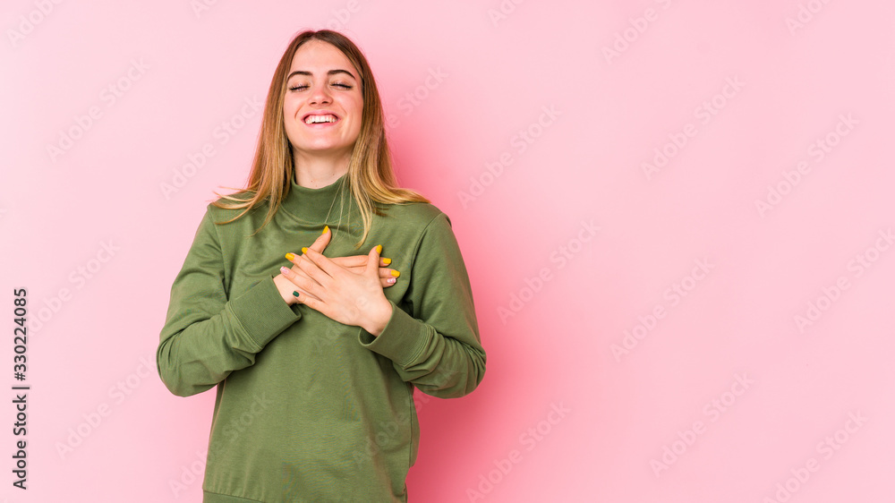 Young caucasian woman isolated on pink background laughing keeping hands on heart, concept of happiness. Young caucasian woman isolated on pink background laughing keeping hands on heart, concept of happiness.