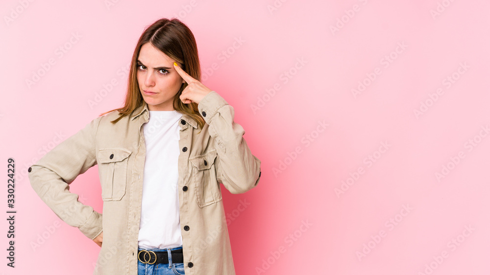 Young caucasian woman isolated on pink background pointing temple with finger, thinking, focused on a task. Young caucasian woman isolated on pink background pointing temple with finger, thinking, focused on a task.