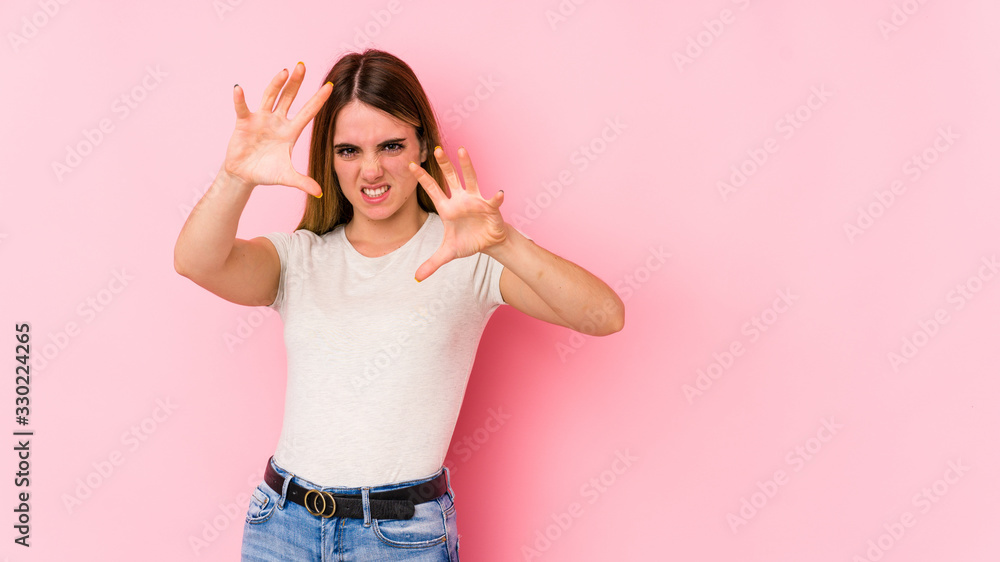 Young caucasian woman isolated on pink background upset screaming with tense hands. Young caucasian woman isolated on pink background upset screaming with tense hands.