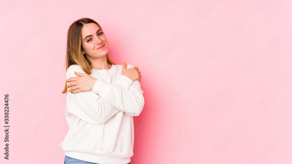 Young caucasian woman isolated on pink background hugs, smiling carefree and happy. Young caucasian woman isolated on pink background hugs, smiling carefree and happy.