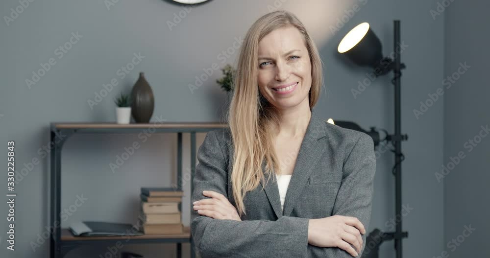 Beautiful mature business woman with blond hair standing at modern office with crossed arms, smiling and looking at camera. Confident lady in formal clothing posing at working place. Beautiful mature business woman with blond hair standing at modern office with crossed arms, smiling and looking at camera. Confident lady in formal clothing posing at working place.
