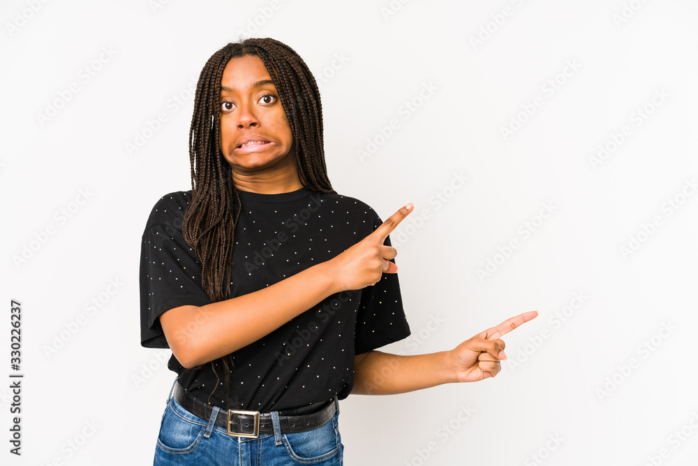 Young african american woman isolated on white background shocked pointing with index fingers to a copy space. Young african american woman isolated on white background shocked pointing with index fingers to a copy space.