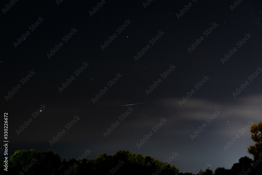 Iridium satellite flare close to Saturn, Antares and Arcturus above wooded horizon