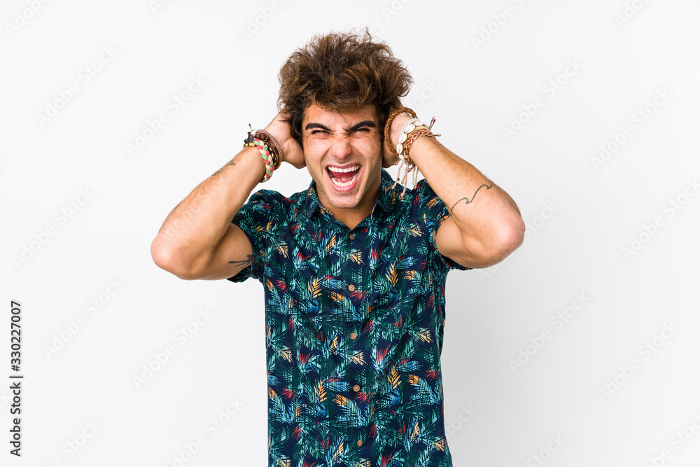 Young caucasian man wearing a flower t-shirt isolated covering ears with hands trying not to hear too loud sound. Young caucasian man wearing a flower t-shirt isolated covering ears with hands trying not to hear too loud sound.