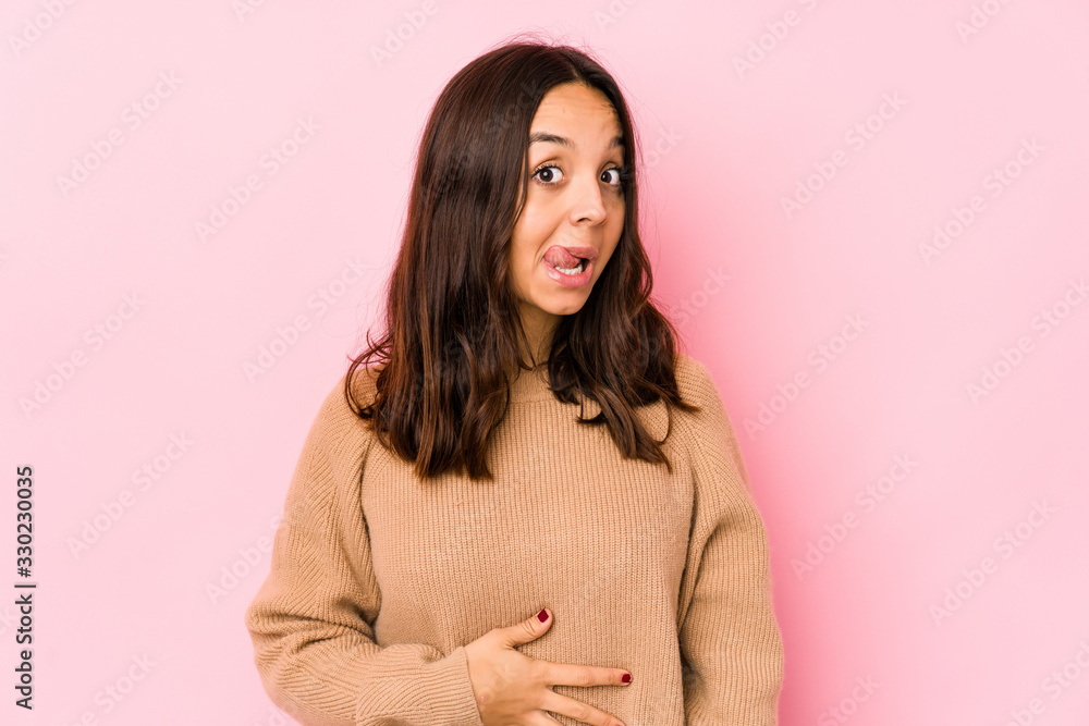 Young mixed race hispanic woman isolated touches tummy, smiles gently, eating and satisfaction concept. Young mixed race hispanic woman isolated touches tummy, smiles gently, eating and satisfaction concept.