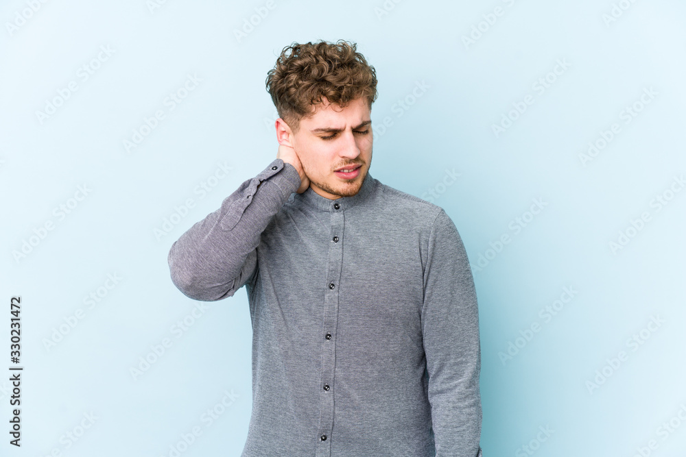 Young blond curly hair caucasian man isolated having a neck pain due to stress, massaging and touching it with hand. Young blond curly hair caucasian man isolated having a neck pain due to stress, massaging and touching it with hand.