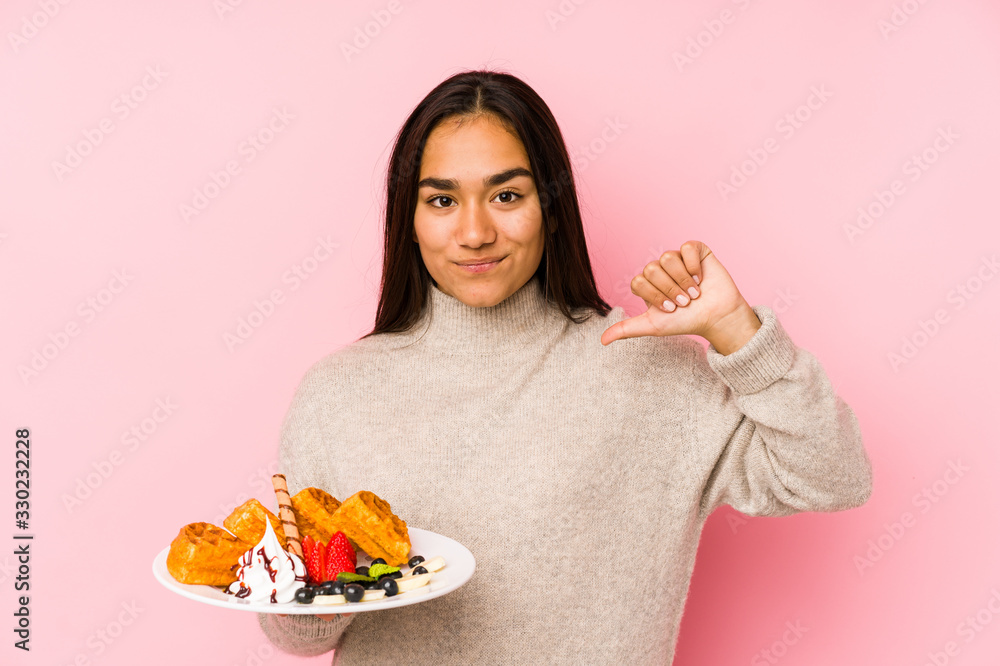 Young asian woman holding a waffle isolated feels proud and self confident, example to follow. Young asian woman holding a waffle isolated feels proud and self confident, example to follow.