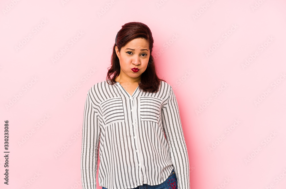 Middle age latin woman isolated on a pink background blows cheeks, has tired expression. Facial expression concept. Middle age latin woman isolated on a pink background blows cheeks, has tired expression. Facial expression concept.