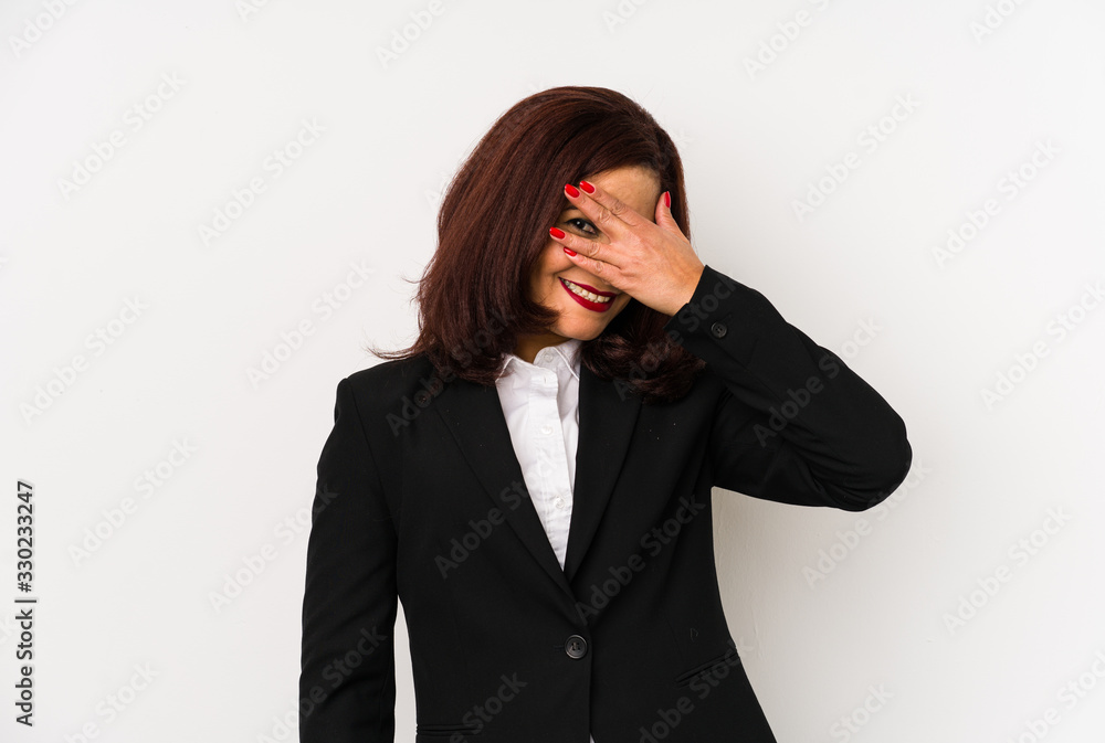 Middle age latin business woman isolated blink at the camera through fingers, embarrassed covering face. Middle age latin business woman isolated blink at the camera through fingers, embarrassed covering face.