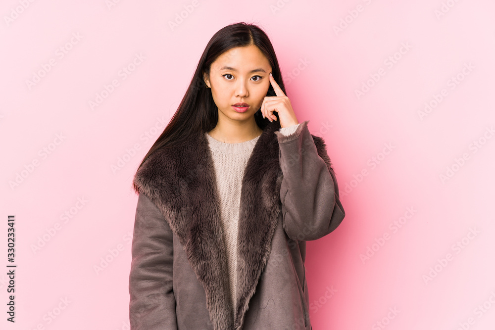 Young chinese woman wearing a coat isolated pointing temple with finger, thinking, focused on a task. Young chinese woman wearing a coat isolated pointing temple with finger, thinking, focused on a task.