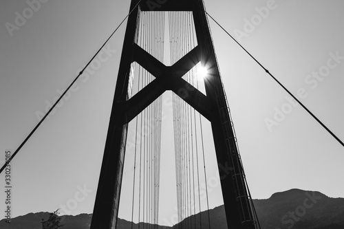 puente colgante con sol en la esquina blanco y negro photo