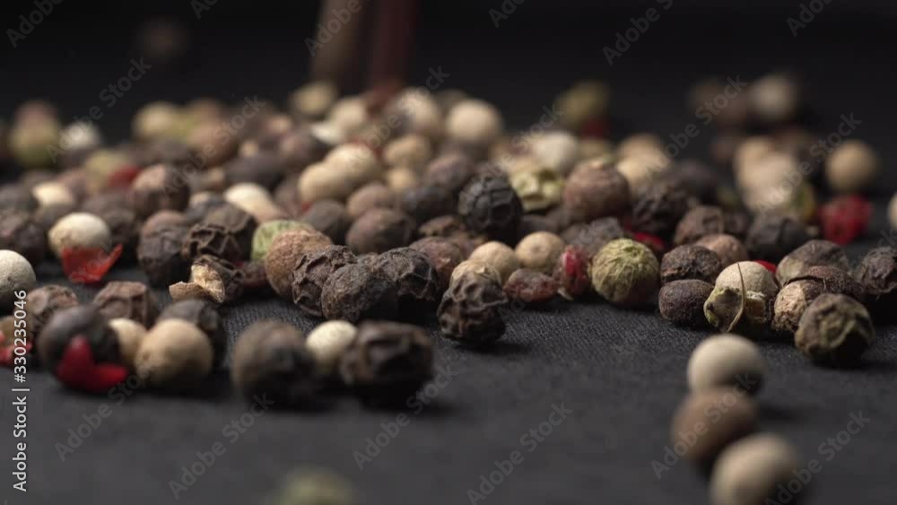 Mixed peppercorns falling on black table in kitchen with black background. Mixed peppercorns falling on black table in kitchen with black background.