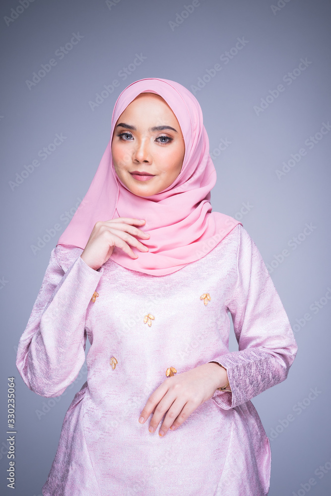 Half length portrait of a beautiful female model wearing traditional dress and hijab, a lifestyle apparel for Muslim women isolated on grey background. Idul Fitri and hijab fashion concept. Half length portrait of a beautiful female model wearing traditional dress and hijab, a lifestyle apparel for Muslim women isolated on grey background. Idul Fitri and hijab fashion concept.