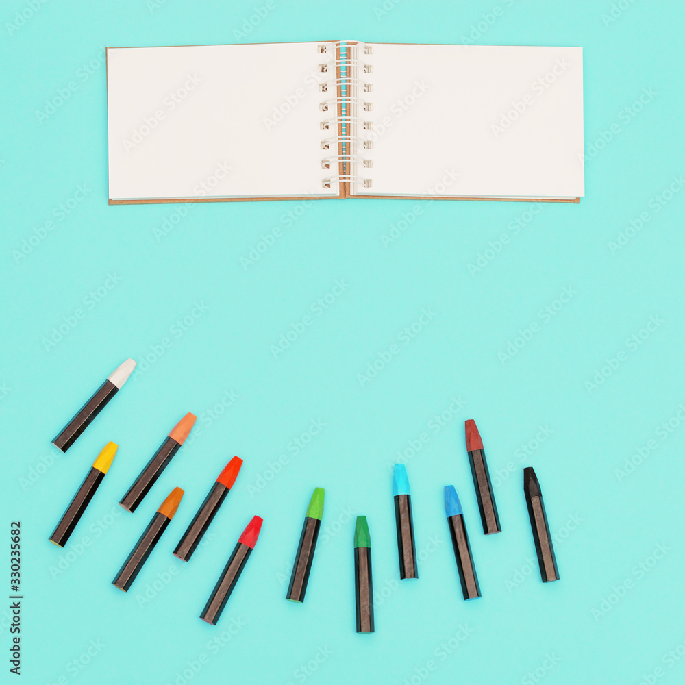 Top view of colored pastel crayons and notebook on spring for sketches. Set of multicolored chalks for creativity. Design background social media. Top view of colored pastel crayons and notebook on spring for sketches. Set of multicolored chalks for creativity. Design background social media.
